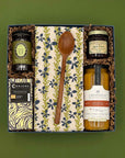 Gift set with a wooden spoon, jars, and a box on a green background