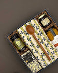 Gift set with jars, a wooden spoon, and a napkin in a decorative box on a dark background