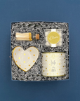 Gift set with candle, heart-shaped dish, matches, and decorative box on a blue background