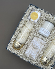 Angled overhead view of the Cheers to You gift box featuring two gold-dipped stemless champagne glasses wrapped in tissue, a Lavender Sage candle, champagne bubble gummies with a gold Cheers seal, botanical-wrapped cookies, and gold-tipped matches in a glass vial.