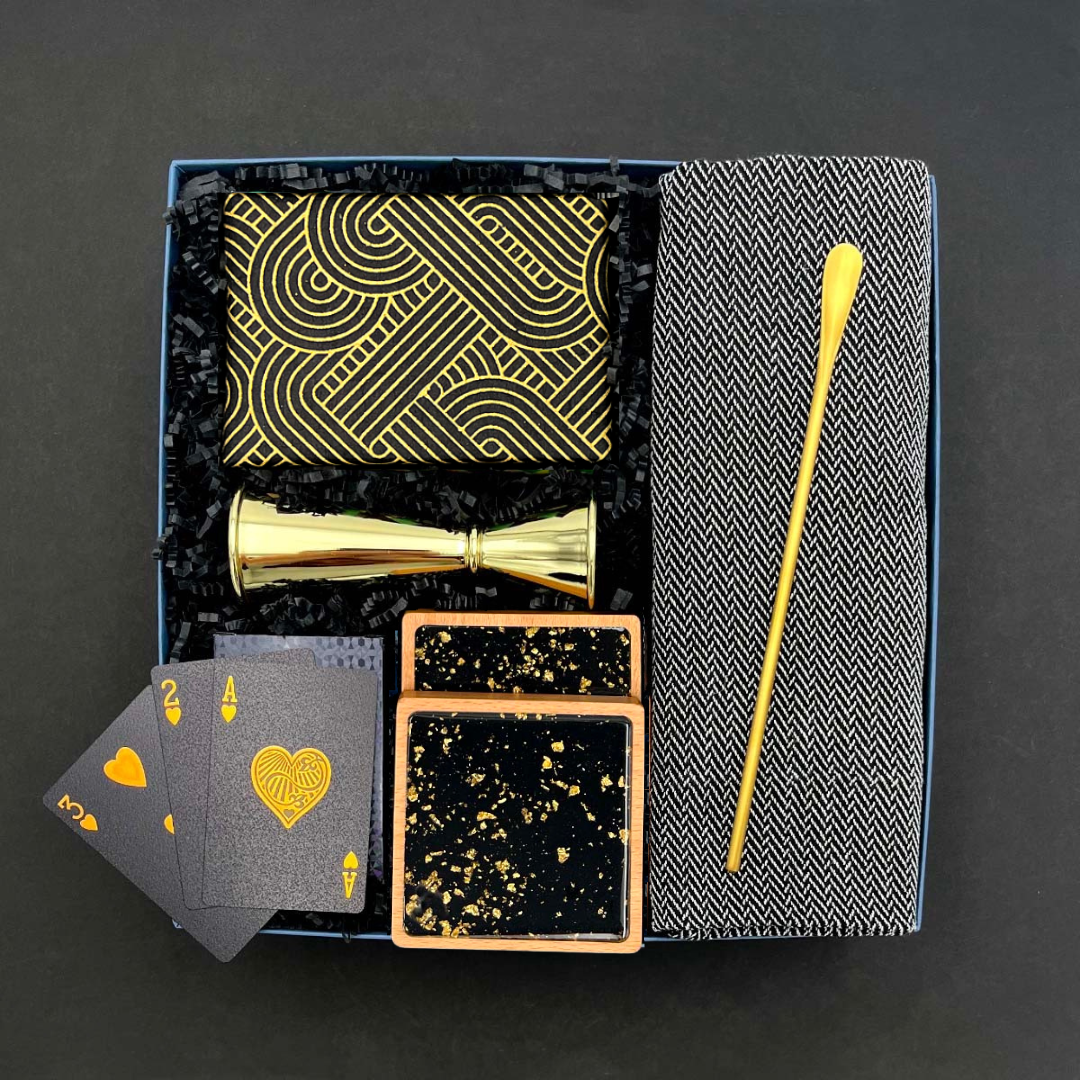 The Cocktail Hour Gift Box with gold bar tools, herringbone towel, coasters, trivia game, and playing cards