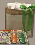Gift bag with a green ribbon and a box of snacks on a beige background