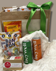 Gift basket with snacks, drinks, and a box on a white blanket