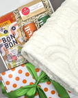 Care Package with snacks and a blanket on a gray surface