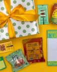 Gift box with yellow ribbon, snacks, and study suppplies on a yellow background