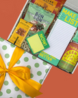 Gift box with snacks, a notepad, and sticky notes on orange background