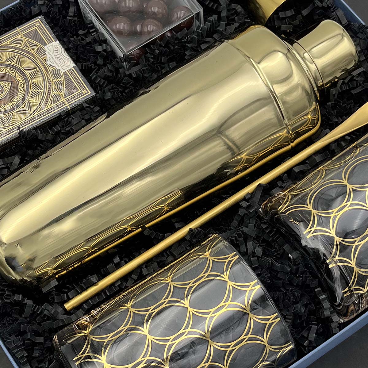 Luxury cocktail gift set with mixology tools, elegant glasses, and sweet treats