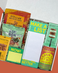 Assorted snacks and a notepad in a box with a colorful design.