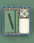Home Office gift box with green journal, black and gold pen, travel tumbler, and colorful confetti caramels on a green background.