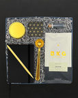 Gift collection including artisan coffee, a gold coffee spoon, candle, matches and a notebook.