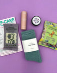 Flat lay of Mood Boost Kit contents including granola, pretzel braids, self care notepad, and cozy cloud socks