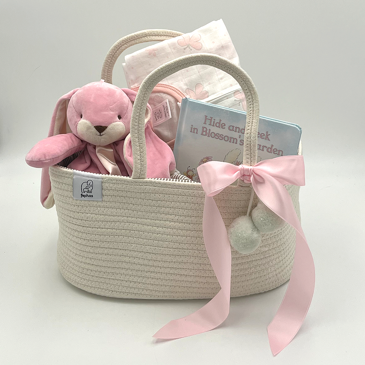 Thoughtful baby girl gift set including plush bunny blanket, cozy sleep sack, illustrated board book, and diaper caddy