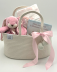 Thoughtful baby girl gift set including plush bunny blanket, cozy sleep sack, illustrated board book, and diaper caddy