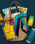 UNCW College Care Package with snacks, a notebook, and a can on a dark blue background