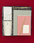 Corporate holiday gift featuring a white MiiR tumbler, festive toffee pretzels, red and green notebooks, and gold pens.