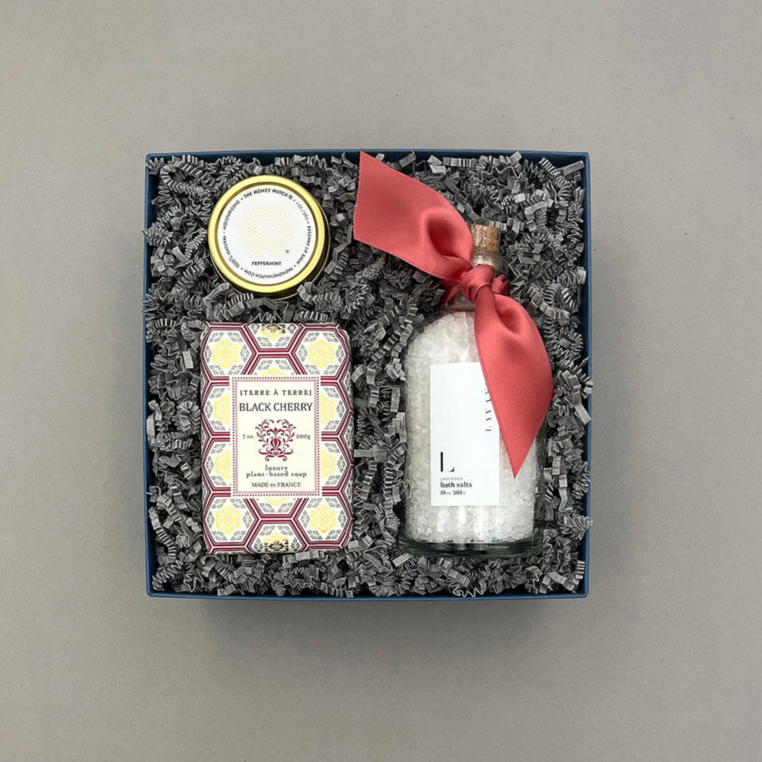 Gift set with a bottle, soap, and decorative items in a box on a gray background