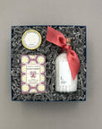 Gift set with a bottle, soap, and decorative items in a box on a gray background
