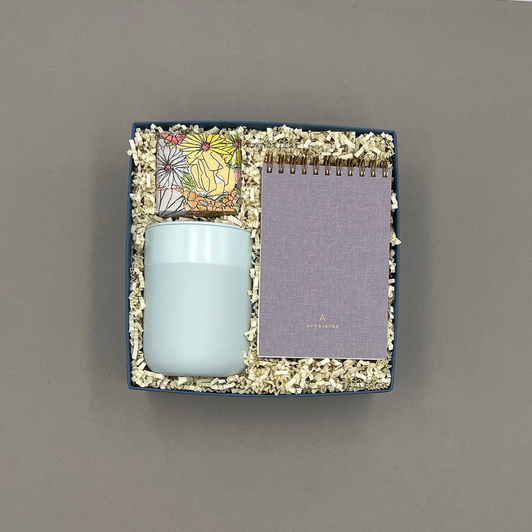 Take Note gift box featuring a mint travel tumbler, lavender pocket notebook, and Champagne Bubbly Bears candy in a white Thoughty box tied with a satin ribbon.