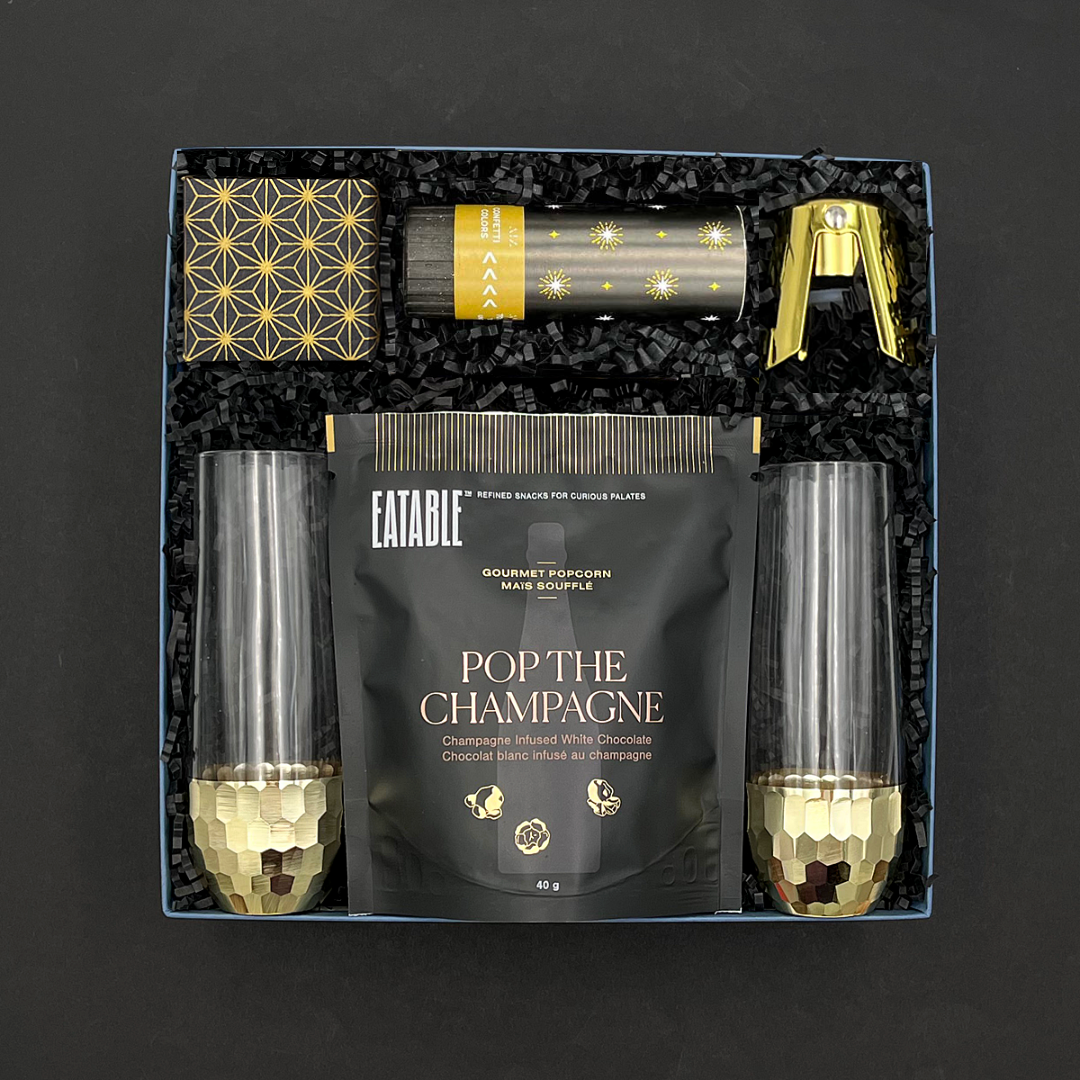 Elegant black and gold celebration gift set with champagne treats and confetti popper