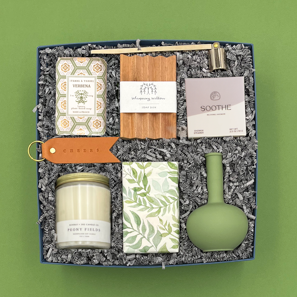 Gift set with candles, soap, and other items on a green background
