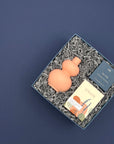 Thoughtful lavender gift with coral vase, botanical soap, and refreshing shower steamer in a blue gift box.