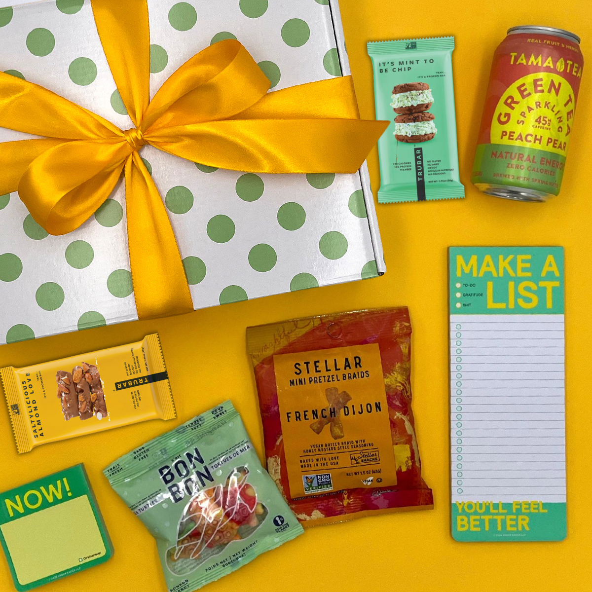 Gift box with yellow ribbon, snacks, and study suppplies on a yellow background