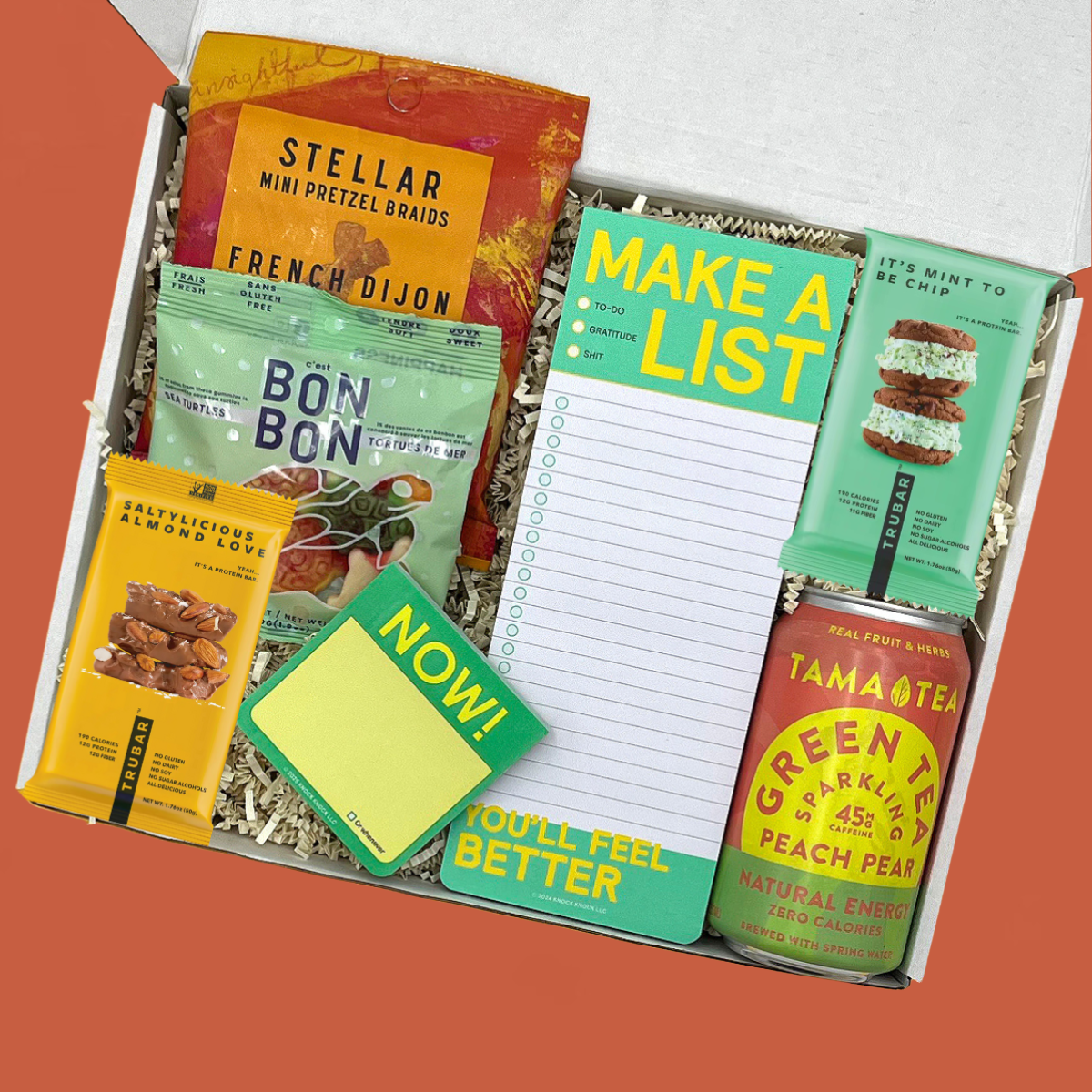Assorted snacks and a notepad in a box with a colorful design.