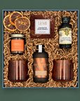 Fireside Gingerbread Old Fashioned gift box with amber cocktail glasses, gingerbread syrup, aromatic bitters, citrus garnish, pecan caramels, and candle.