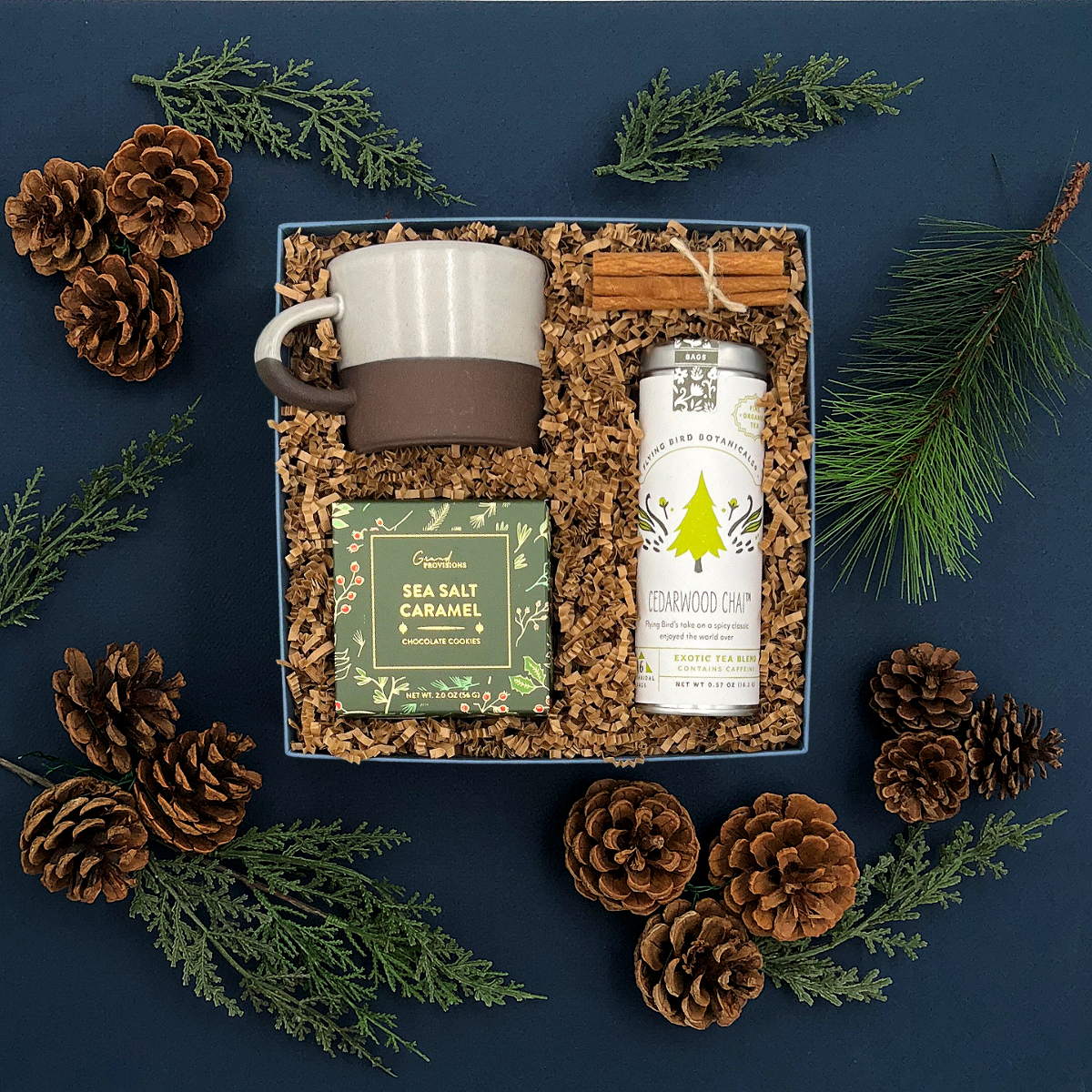 Fraser Gift Box with chai tea, holiday cookies, ceramic mug, and cinnamon sticks.