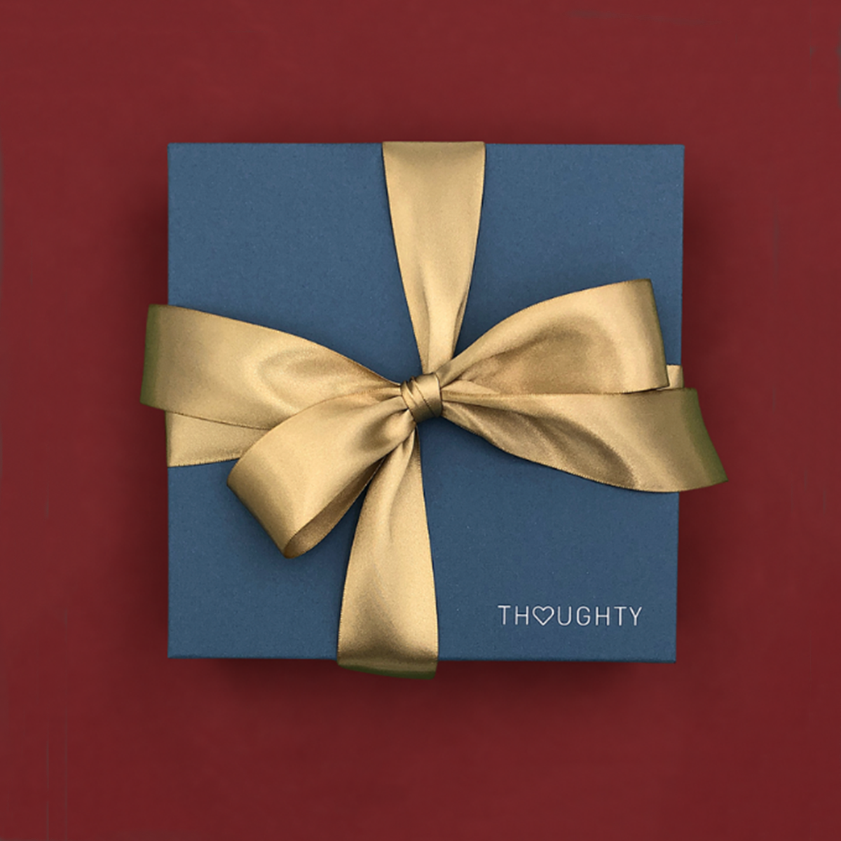 Thoughty holiday gift box tied with a gold satin ribbon.