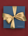 Thoughty holiday gift box tied with a gold satin ribbon.