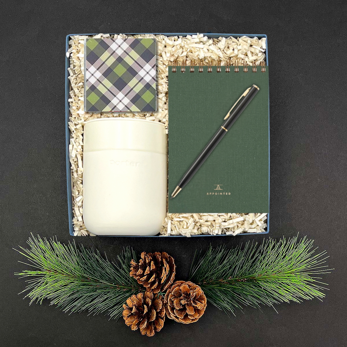 Holiday Good Tidings Gift Box featuring tumbler, green notebook, and chocolate caramels.