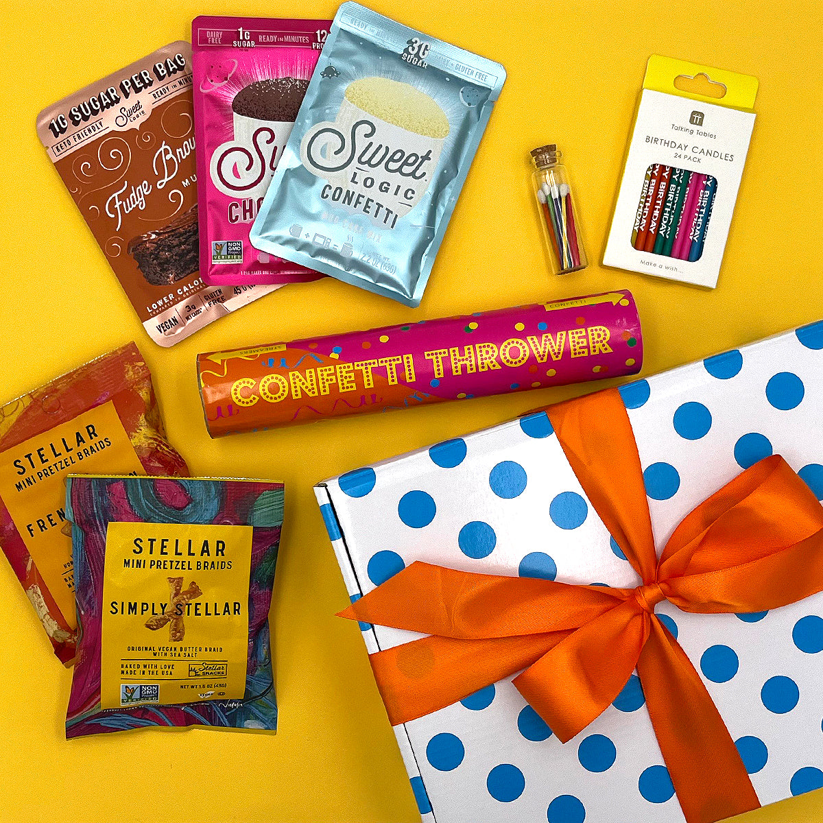 Assorted birthday treats including candy, confetti, and a gift box on a yellow background