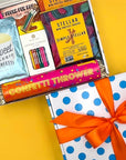 Gift box with confetti-themed items including candles and a 'Simply Stellar' product on a yellow background.