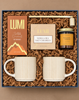 Hearth cozy gift box with stoneware mugs, salted caramel hot chocolate, vanilla sea salt caramels, candle, and gold candle snuffer.