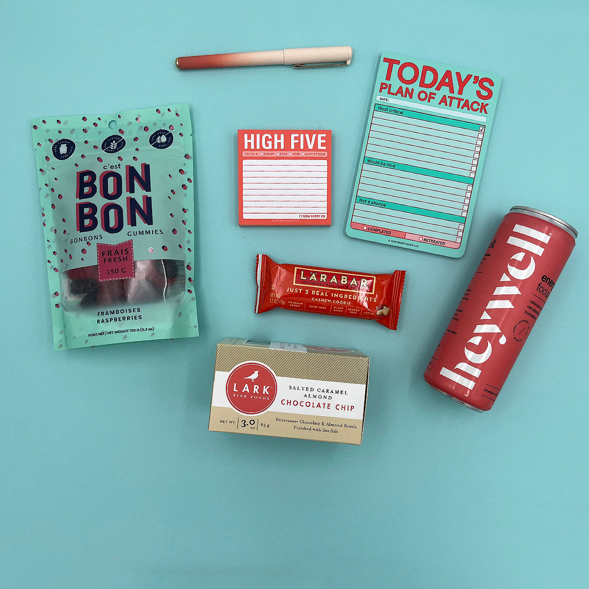 Flat lay of High Five Kit contents including Larabar, raspberry gummies, gradient pen, and sparkling energy drink