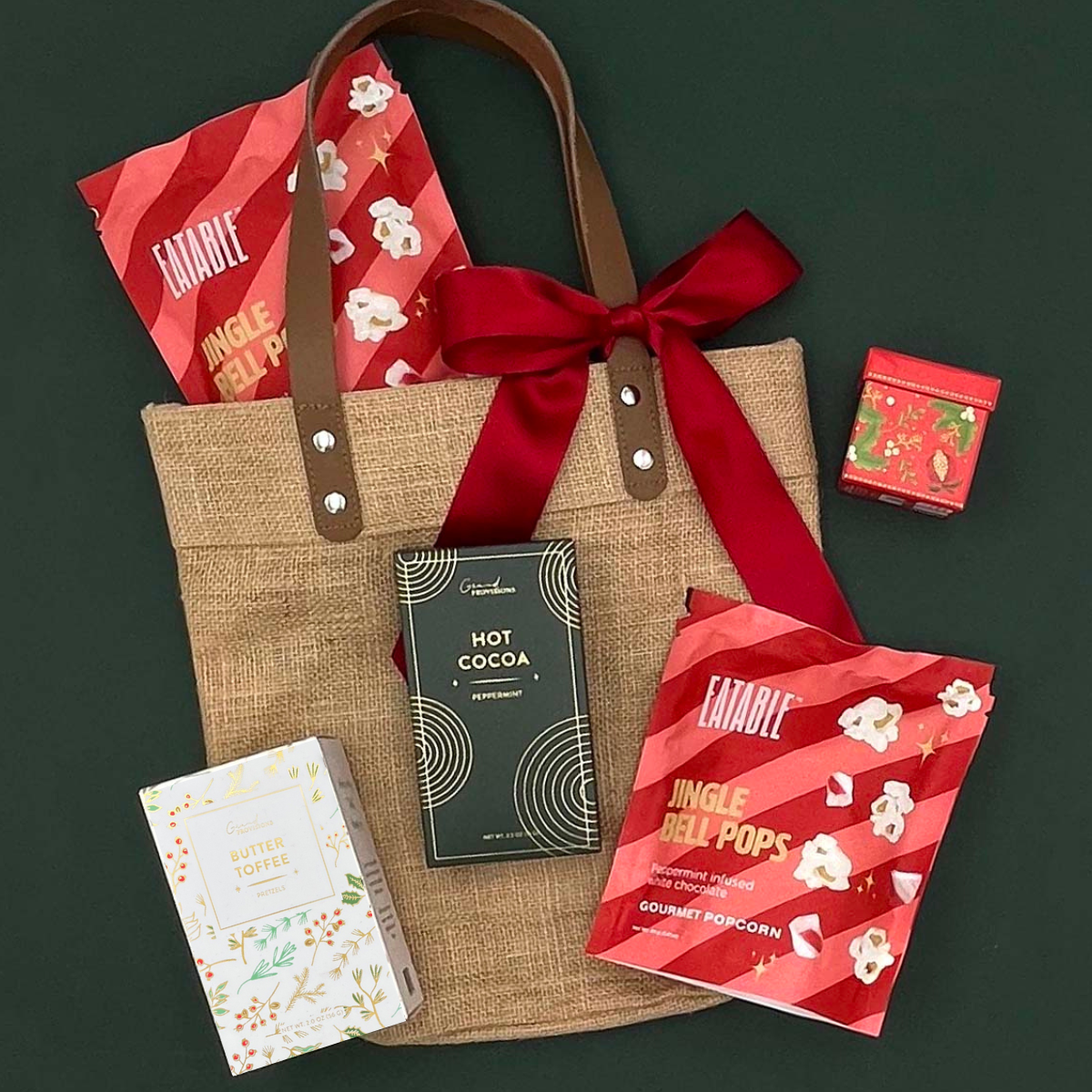 The Holiday Tote by Thoughty — gourmet holiday gift set in a jute tote with leather handles, featuring cookies, popcorn, pretzels, and festive treats.
