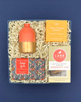 Just Because gift box with coral and gold bud vase, orange spice soap, shower steamer, and salted caramel almond chocolate chip cookies.