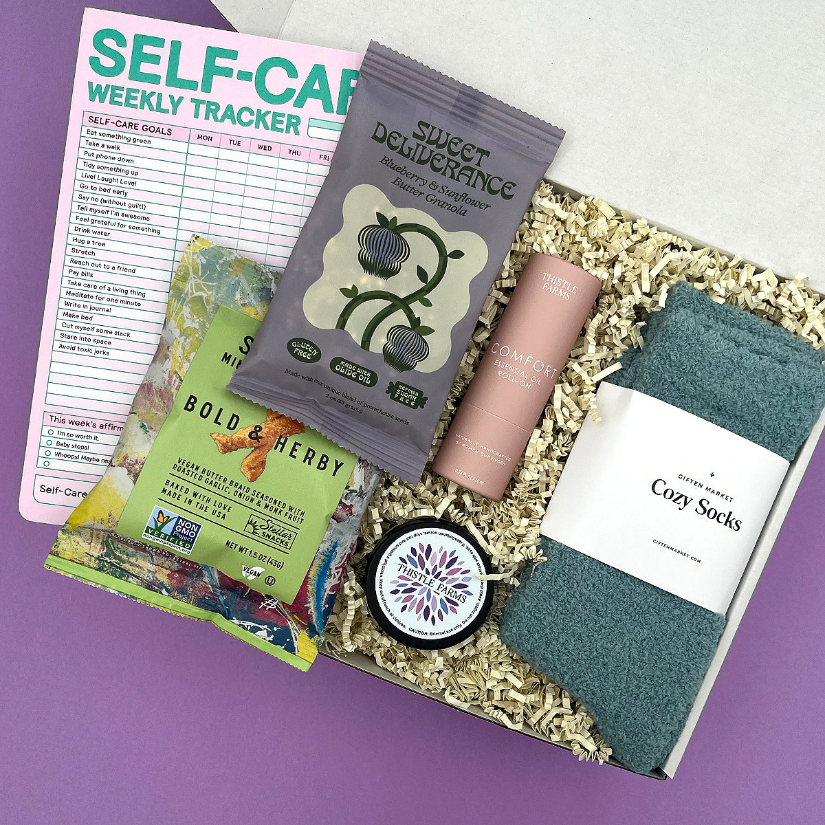 Mood Boost Kit care package with lavender body butter, cozy socks, essential oil roll on, and snacks in a gift box