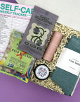 Mood Boost Kit care package with lavender body butter, cozy socks, essential oil roll on, and snacks in a gift box