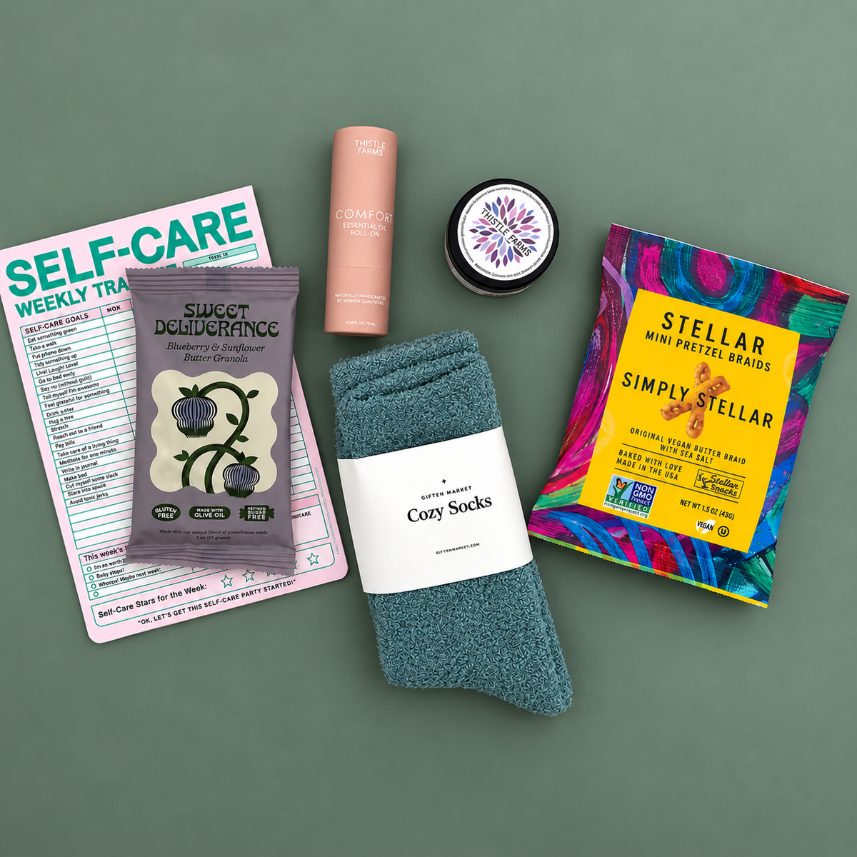 Flat lay of Mood Boost Kit contents including granola, pretzel braids, self care notepad, and cozy cloud socks.
