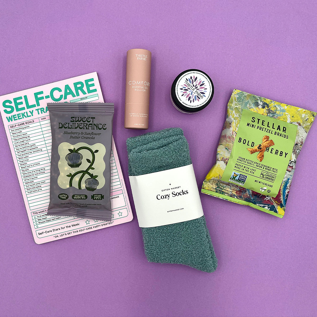 Flat lay of Mood Boost Kit contents including granola, pretzel braids, self care notepad, and cozy cloud socks