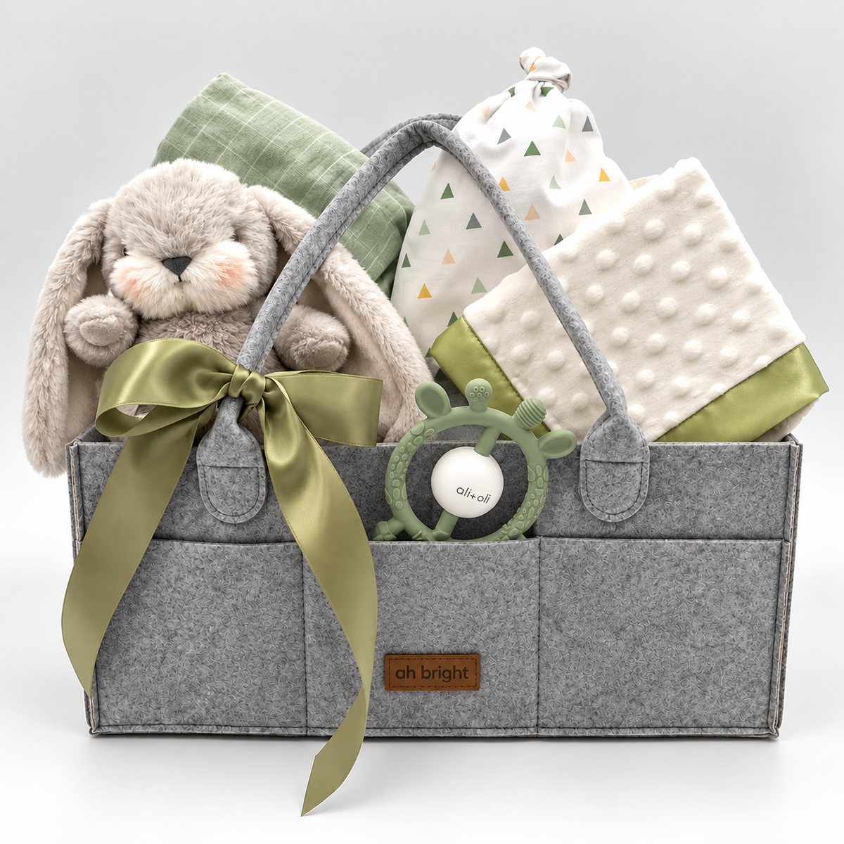 Baby shower gift featuring newborn essentials: blanket, lovie, stuffed bunny, and baby hat in an organized diaper caddy