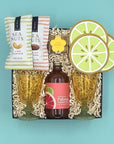 Gift set with Paloma bottle, lime-themed coasters, and sea nut snacks on a blue background
