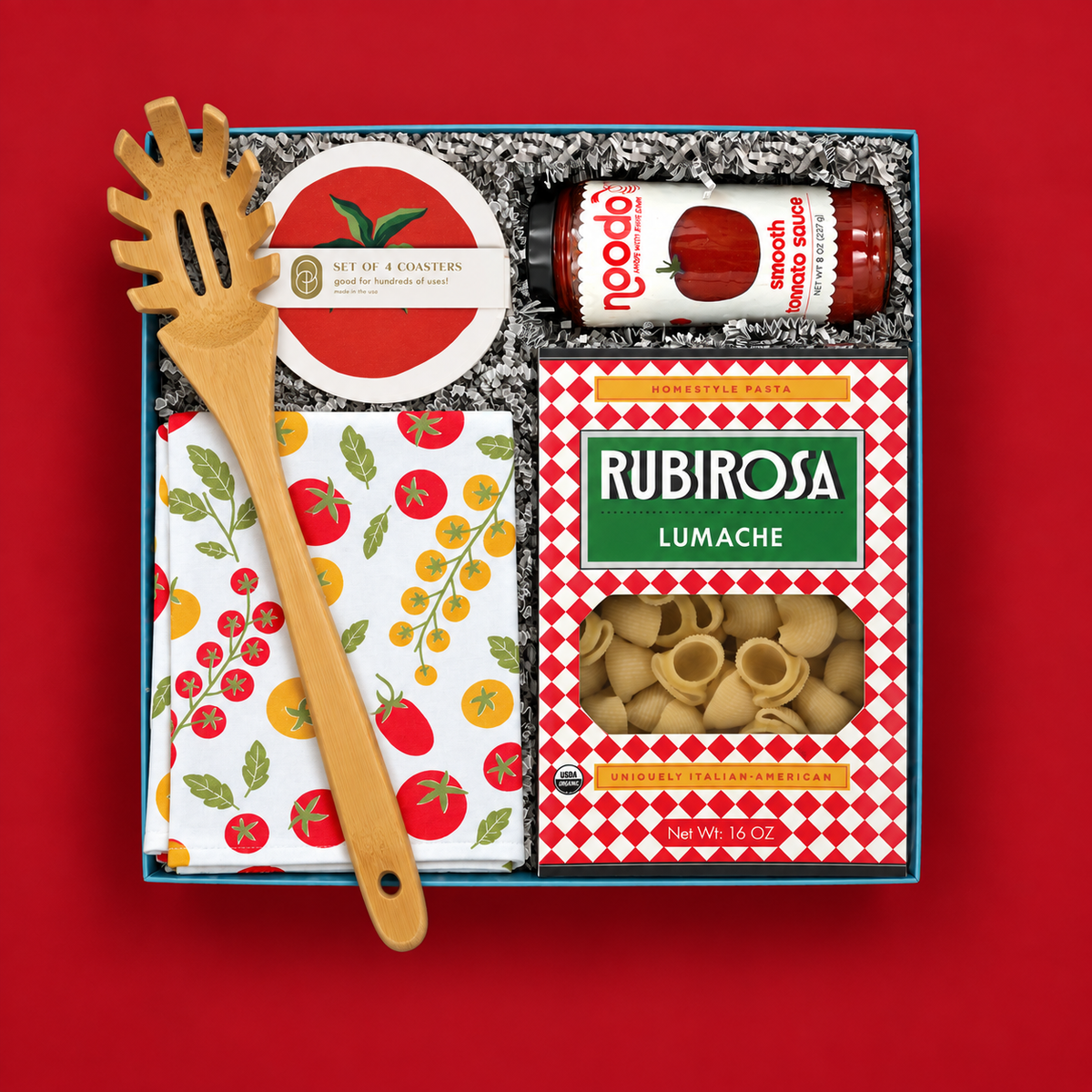 Italian-inspired pasta gift with Rubirosa lumache pasta, tomato sauce, colorful tomato towel, coasters, and bamboo pasta server.