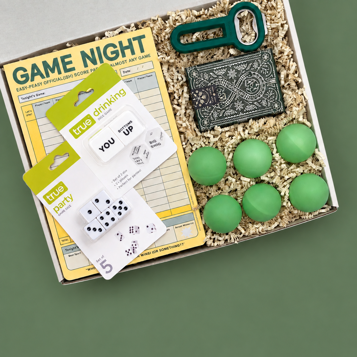 Box of college party supplies including cards, dice, and green balls on a blue background