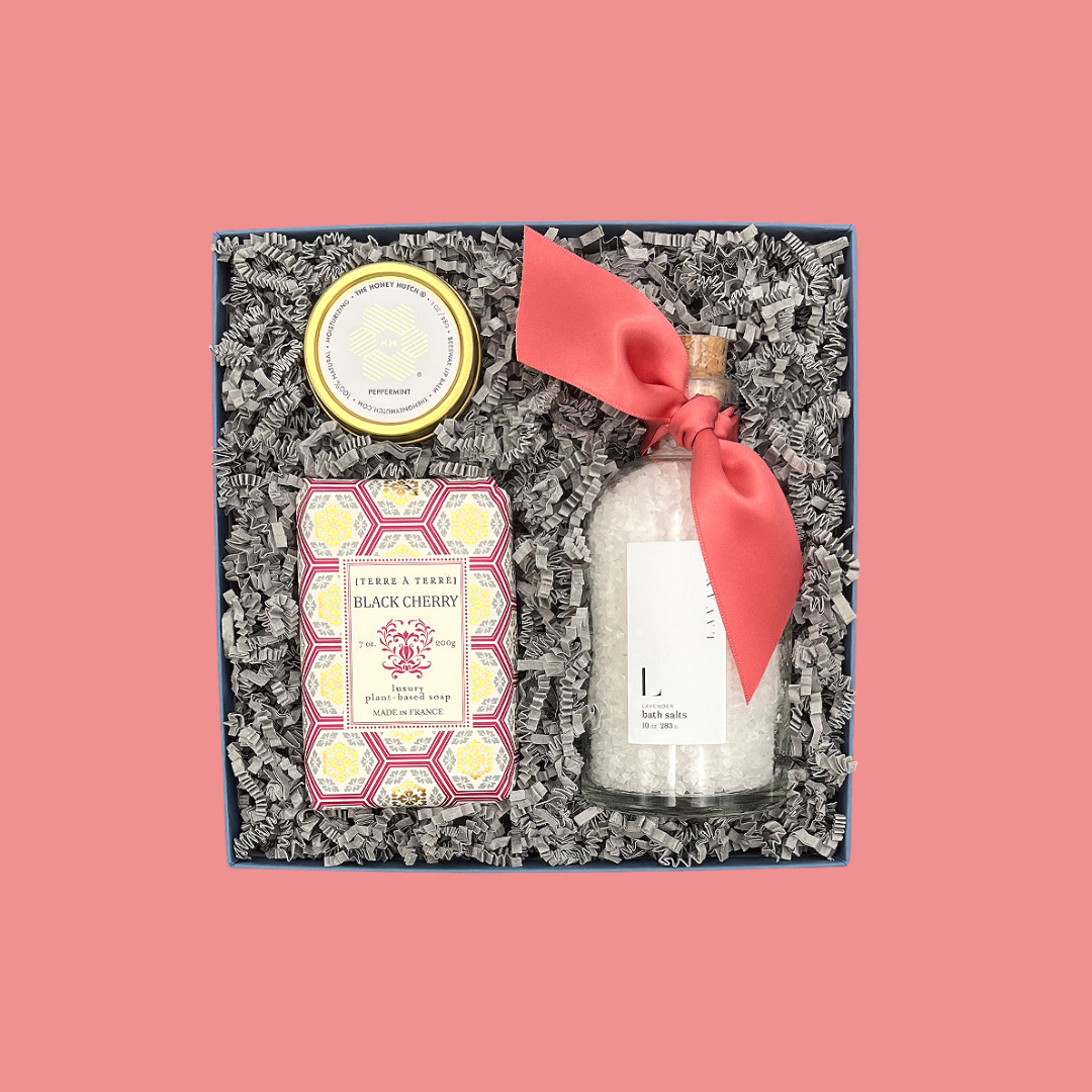 Gift set with bath salts, soap, and candle on a pink background