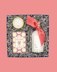 Gift set with bath salts, soap, and candle on a pink background
