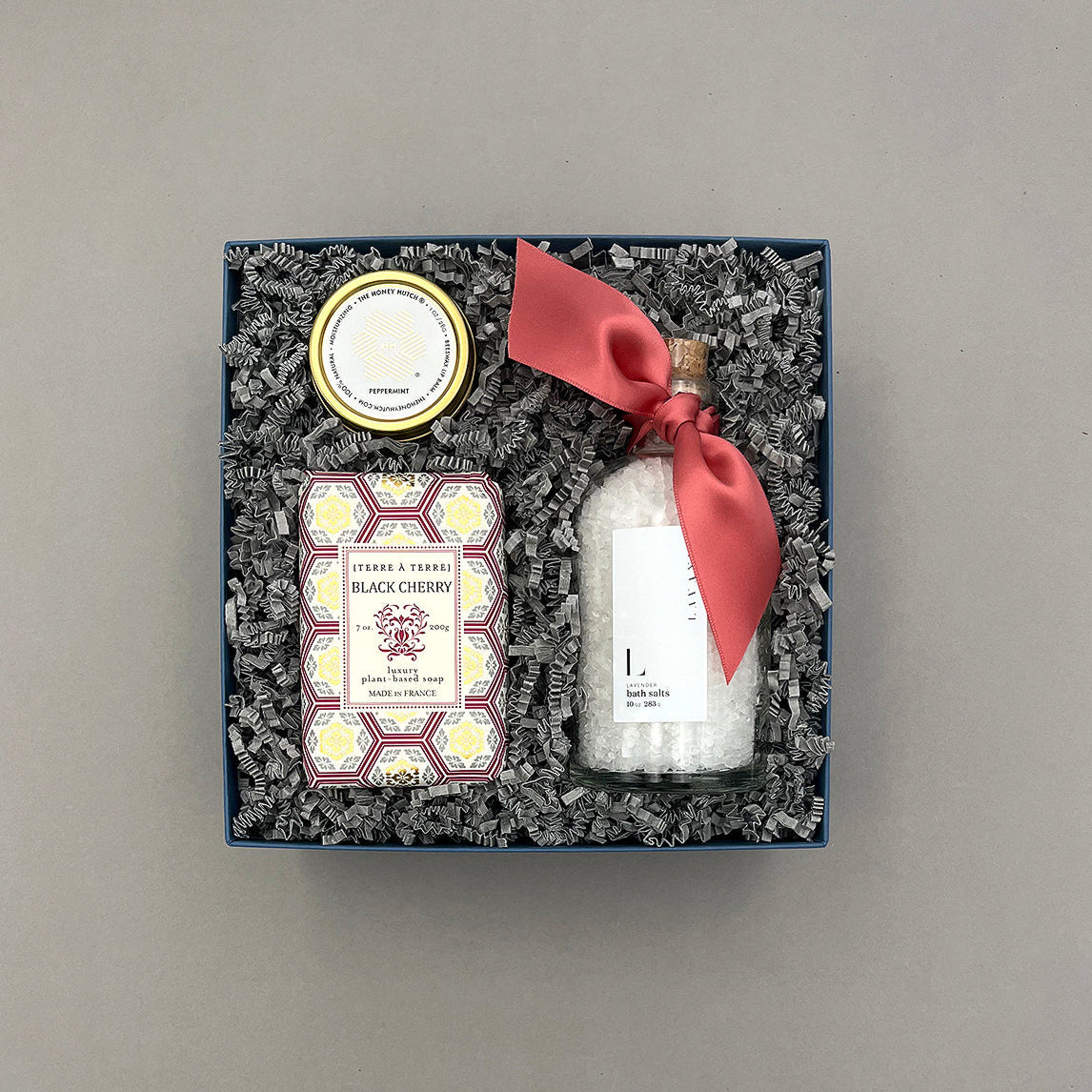 Gift set with a bottle, soap, and decorative items in a box on a gray background