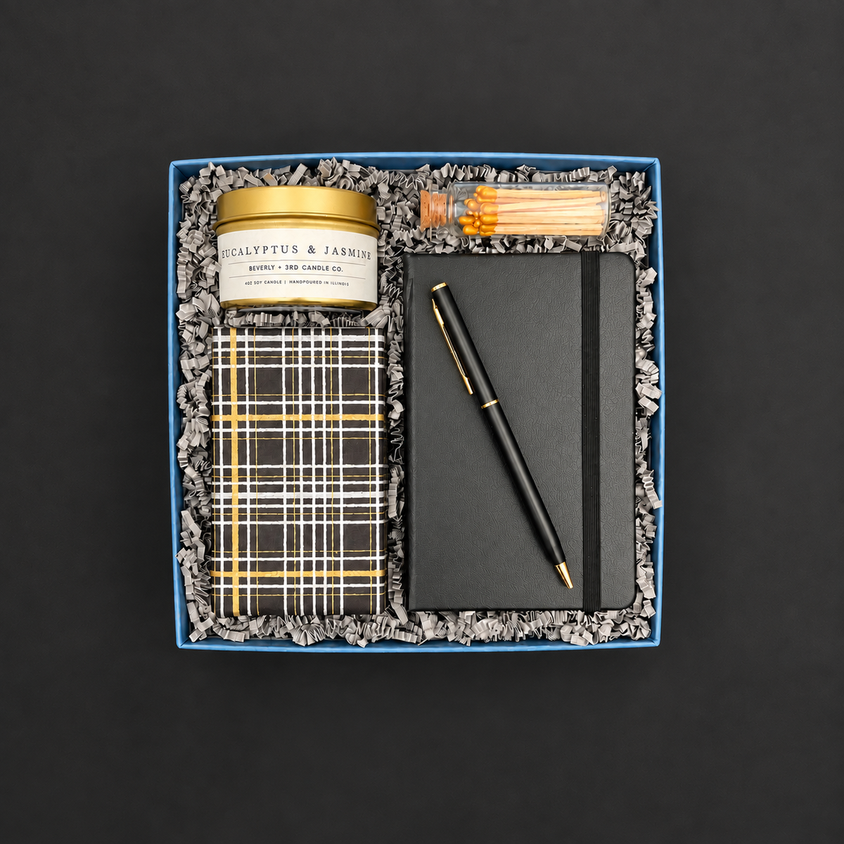 Take Note gift box with black notebook and pen, eucalyptus jasmine candle, gold matches, and gift-wrapped chocolate chip cookies.